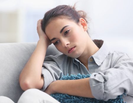 Depressed young woman on sofa at home, closeup